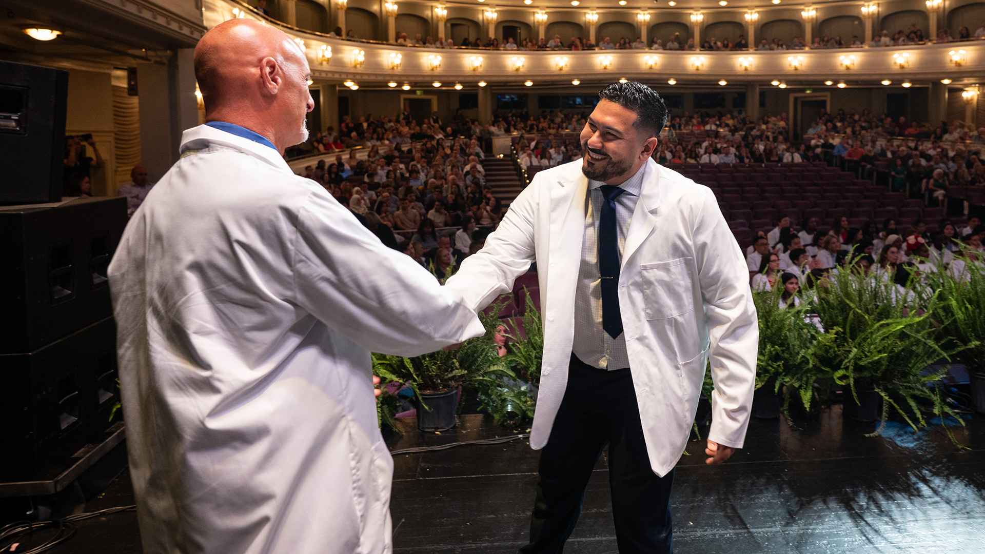 College dean in white coat greeting student