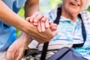 Elderly patient holding hands with caregiver