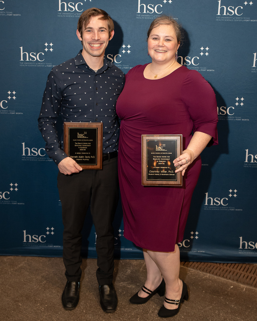 Two people posing with an award 