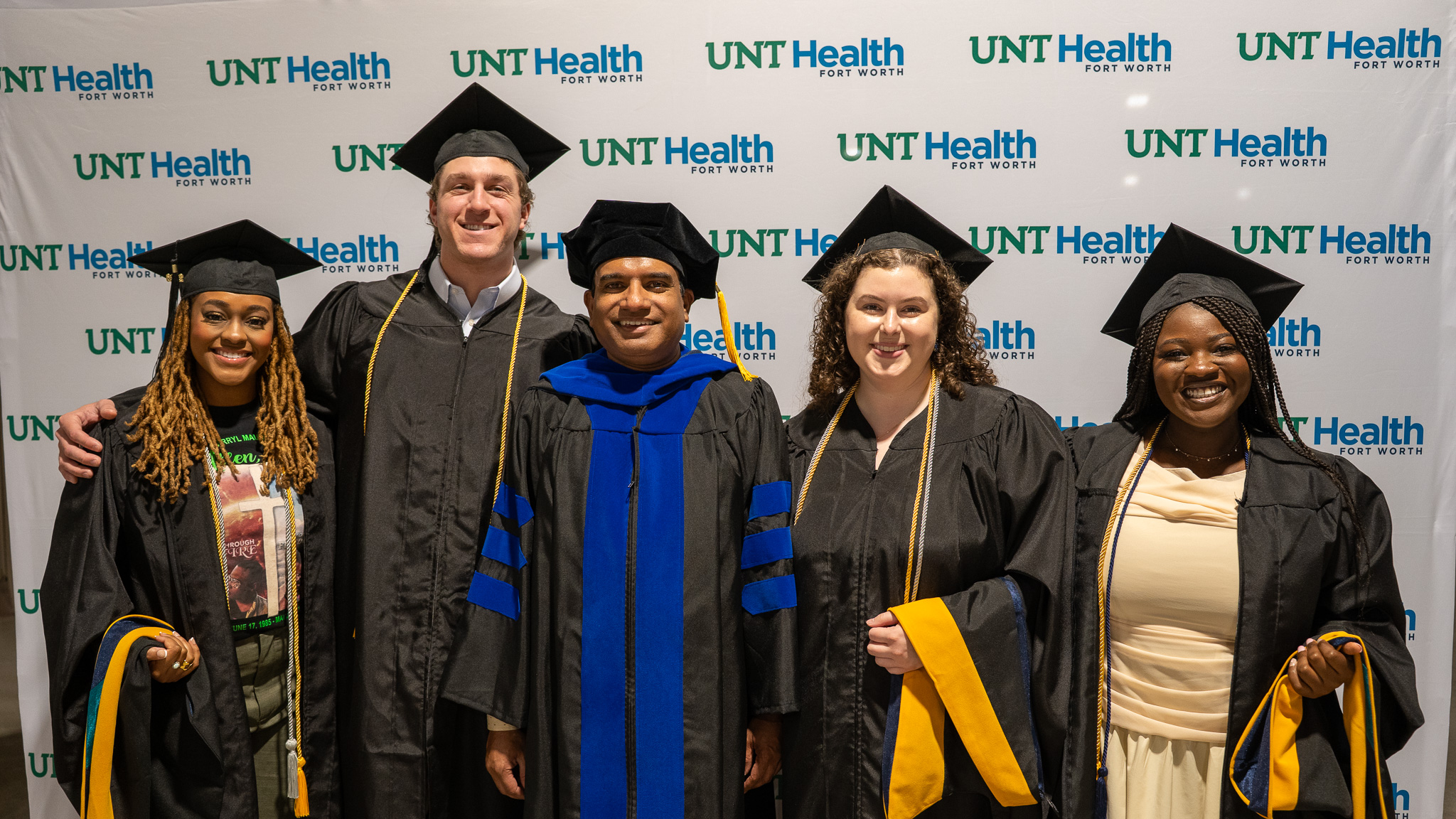 CRM Grads in Regalia in Front of UNT Health Backdrop