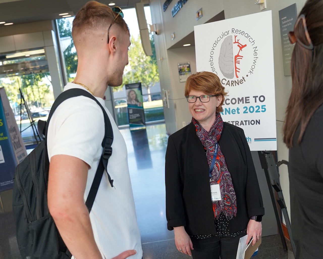 Two conference attendees in front of a CARNet poster