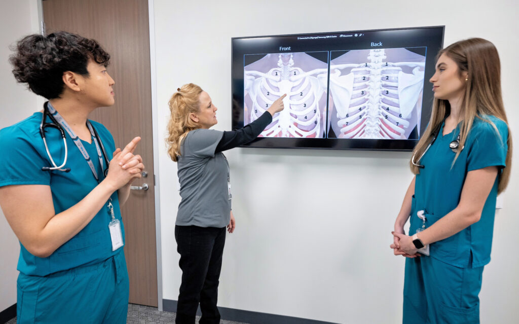 Nursing students look at instructor reading an X-ray.
