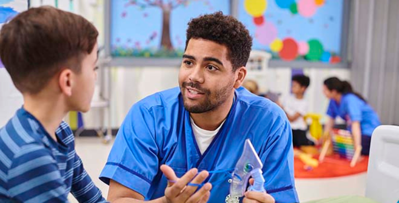 Male nurse showing a young boy about an inhaler he has in his hand
