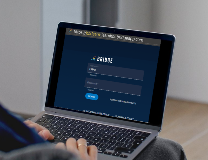 A person using a laptop shows the Bridge login screen with fields for email and password. 