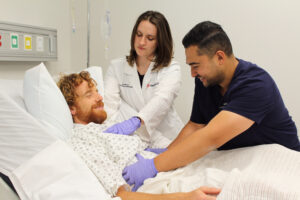 Image of doctor and resident assessing a patient in the hospital.